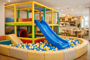 Two-level soft play frame with ball pit and slide in a bright indoor play café