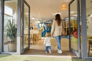Parent and toddler arriving at a bright family play cafe